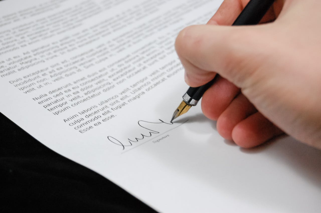 A hand holding a fountain pen signing a document