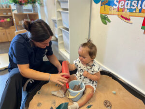 a child playing in a sandpit with an early years practitioner