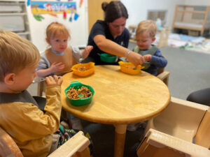 Children sat around a table eating with an early years practitioner
