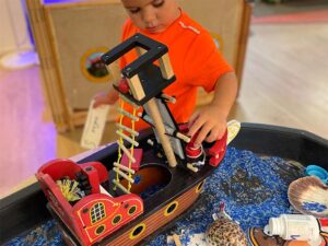 A child playing with a wooden pirate ship