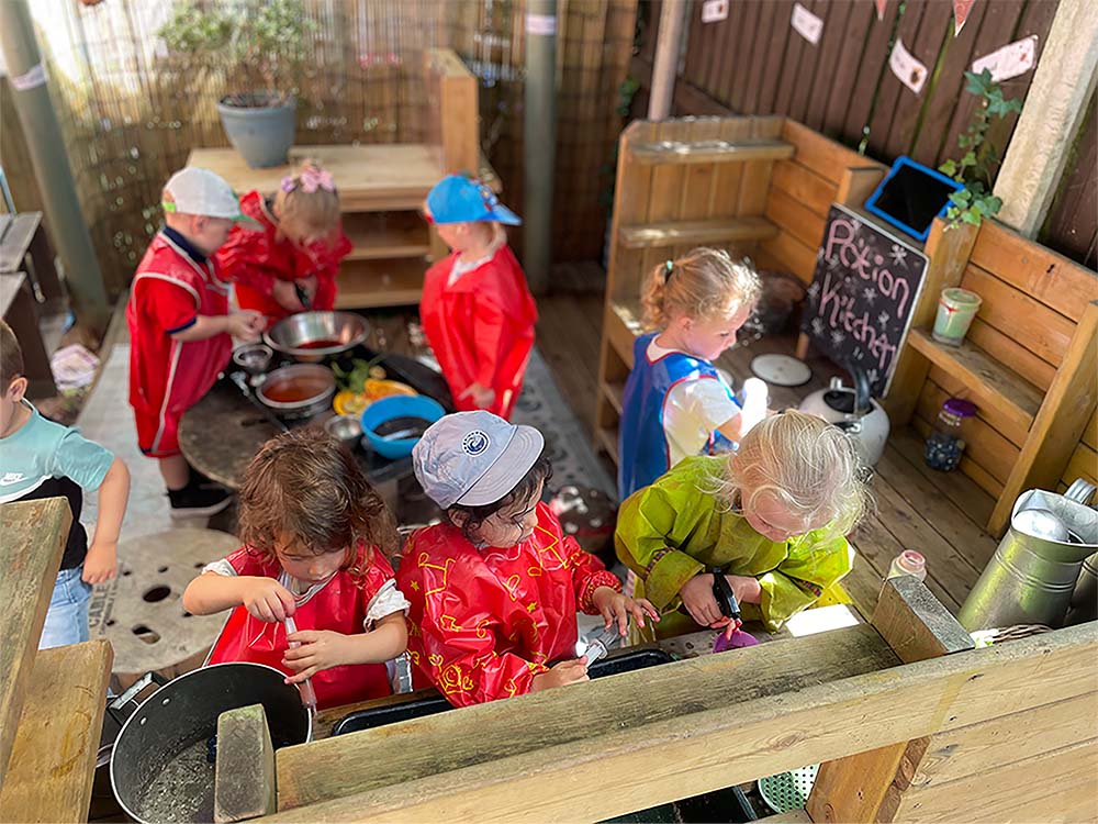 Children playing in an outdoor kitchen with food