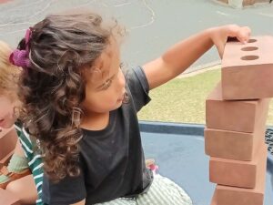 Child stacking foam bricks outside