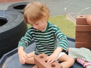 Child stacking foam bricks outside