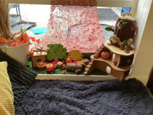 Blankets & cushions on the floor next to a window with outdoor themed toys