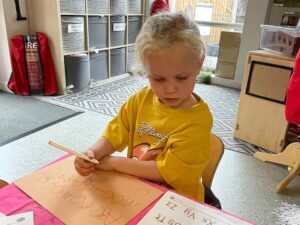 A child sat at a table practising writing their alphabet